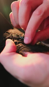 A master sews national Arab clothes abay with a needle and thread in his atelier