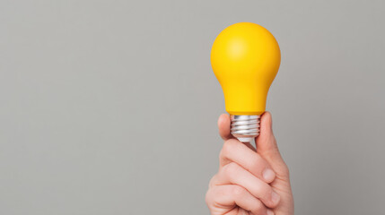 Hand holding yellow light bulb innovation idea creativity concept, gray background, inspiration, motivation, business, success