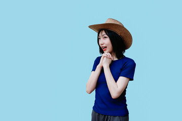 Young woman wearing a cowboy hat expresses excitement against a solid blue backdrop in a playful...