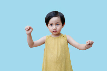 Young child wearing a yellow sleeveless top poses against a light blue background while showcasing...