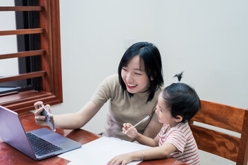 Mother and child engage in online learning together at home during the day