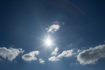 Sun is radiating rays in flat design with cumulus clouds and lens flare, copy space © vectorfusionart