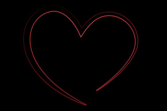 Red neon heart outline is glowing against solid black backdrop in flat design, copy space