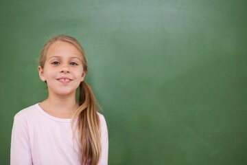Flat design child is standing wearing pink shirt in front of green chalkboard, copy space