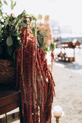 A rustic floral arrangement featuring cascading red amaranthus and lush greenery, captured in warm...