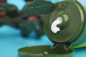 A close-up view of a green tube with a olive cream .