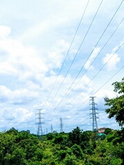 Two towering high-voltage power pylons stand majestically on a green hillside in Pakse, Laos,...