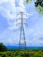 Electric utility pole on a forested hill, with wide panoramic sky and white clouds enhancing the...