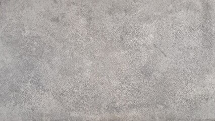 Fototapeta premium A rough, mottled gray surface, likely concrete or stone, with subtle variations in texture and shading