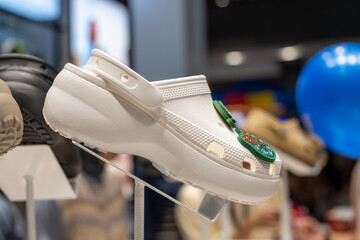 White platform clogs with colorful decorative charm on display in a trendy fashion store. Minimalist footwear design stands out with clean texture and elevated sole in retail lighting.