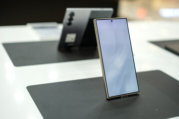 Modern smartphone with large display and flat-edge design showcased on a retail table, highlighting premium and minimalist technology in a store environment.