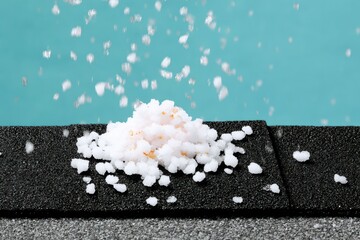 Closeup of White Granules Falling onto Black Asphalt