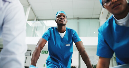 Team, surgeon and black man pushing stretcher for surgery, medical help and injury in hospital. Clinic POV, rush or low angle of doctor with scrubs and bed for healthcare services, risk and emergency