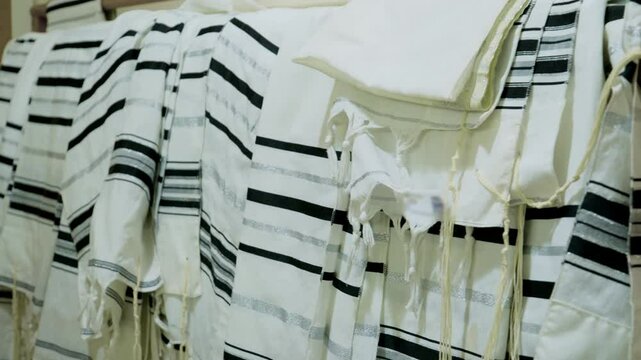 The tallit Jewish prayer shawls hanging neatly, in the synagogue or place of worship. The tallitot with knotted fringes tzitzit.