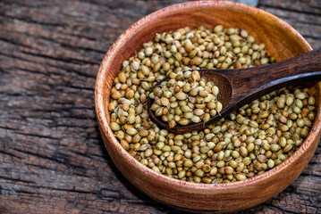Spice coriander (Coriandrum sativum) seeds in wooden bowl and spoon on wooden background. Indian...