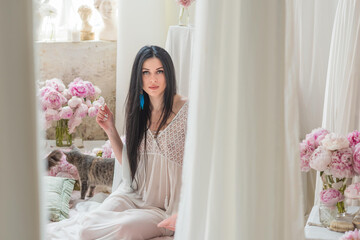 A brunette woman stands quietly in the morning light, wrapped in a sheer white vintage gown, ...