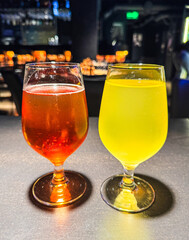 Two glasses of different colored drinks sit on a table