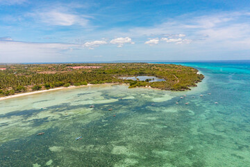 Island with coconut trees and fishing boat over the clear sea water surface. Bantayan, Cebu, Philippines.