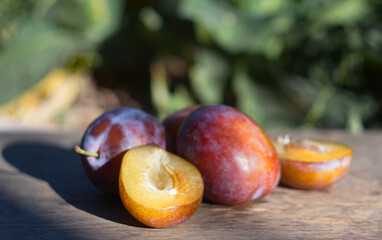 Cut and whole plums on a board in nature