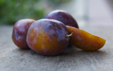 Cut and whole plums on a board in nature
