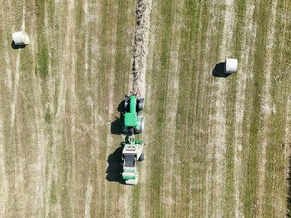 A tractor with a baler in the field, shot with a drone