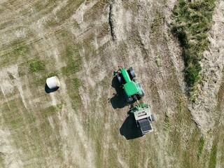 A tractor with a baler in the field, shot with a drone