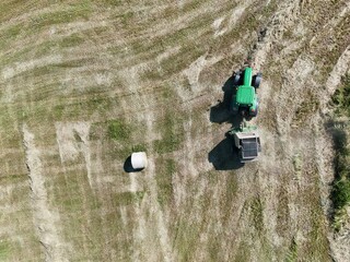A tractor with a baler in the field, shot with a drone