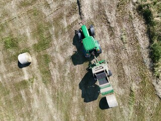 A tractor with a baler in the field, shot with a drone