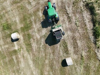 A tractor with a baler in the field, shot with a drone
