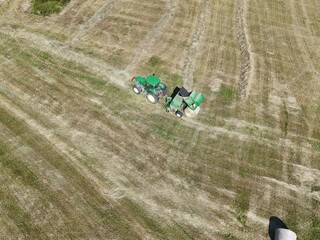 A tractor with a baler in the field, shot with a drone