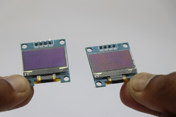 OLED screen with working and broken display held in the hand side by side on a white background