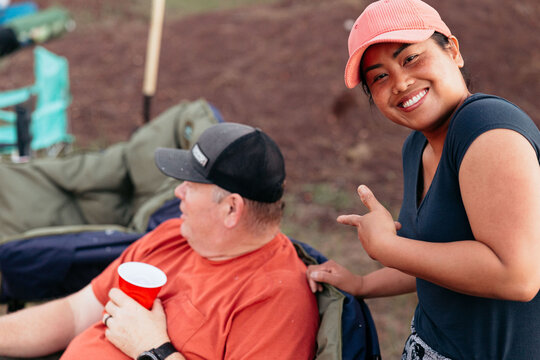 Smiling woman points playfully at seated man during camping trip - Powered by Adobe