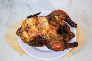 Roasted chicken whole on white plate	
