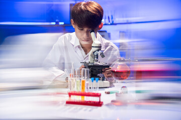 Young Scientist Examining Specimen Under Microscope in Laboratory