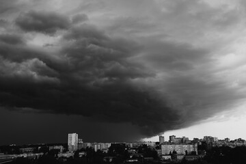 Black and white frame. Dark, heavy storm clouds are gathering over the city's skyline. Impending...
