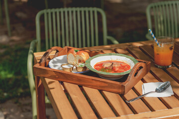 Delicious Ukrainian borscht with pear served on a wooden tray in a street cafe.