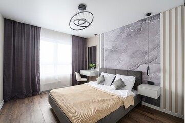 stylish bedroom features a bed with neutral bedding, marble wallpaper, and modern lighting....