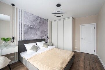 cozy bedroom with a grey upholstered bed, white linens, and a beige throw. The room features a...