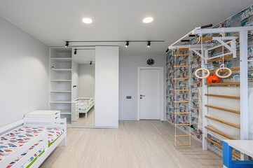 Bright child's room featuring a bed, closet with mirror, gym, wooden floor, and a white door
