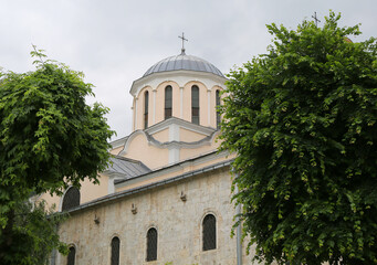 Dome with cross of St George Cathedral  building between tree and plants in Prizren, Kosovo