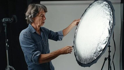 Photographer Adjusting Studio Lighting Reflector