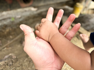 The baby's hand holds his father's hand
