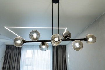 A beautiful and elegant chandelier is gracefully hanging from the ceiling in the living room,...