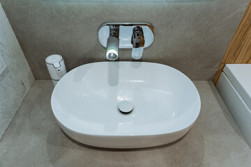 A white sink is placed in a bathroom, featuring a sleek faucet attached to it, making it both a functional plumbing fixture and an essential part of the bathrooms interior design