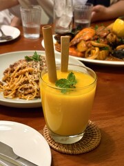Plated mango juice in a glass with an organic wooden straw.