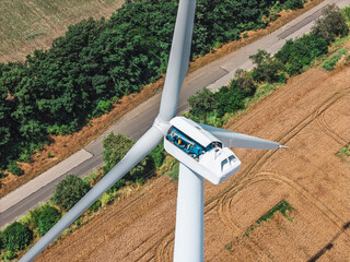 High-altitude repair work on modern wind turbine in rural field © glebzter