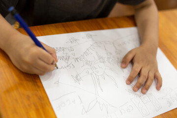 Baby hand holding pencil and drawing on white paper. 