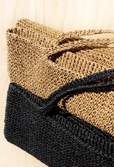 Black and beige ECO raffia bags on wooden background.