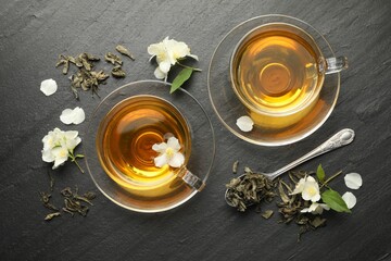Aromatic jasmine tea, brew and flowers on grey table, flat lay
