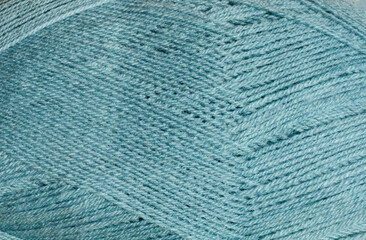 The texture of the turquoise wool ball shows the tightly twisted threads.